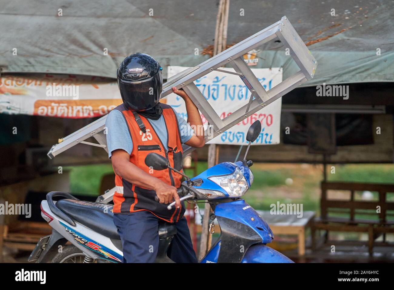Un motociclista di taxi che porta una scala. Foto Stock