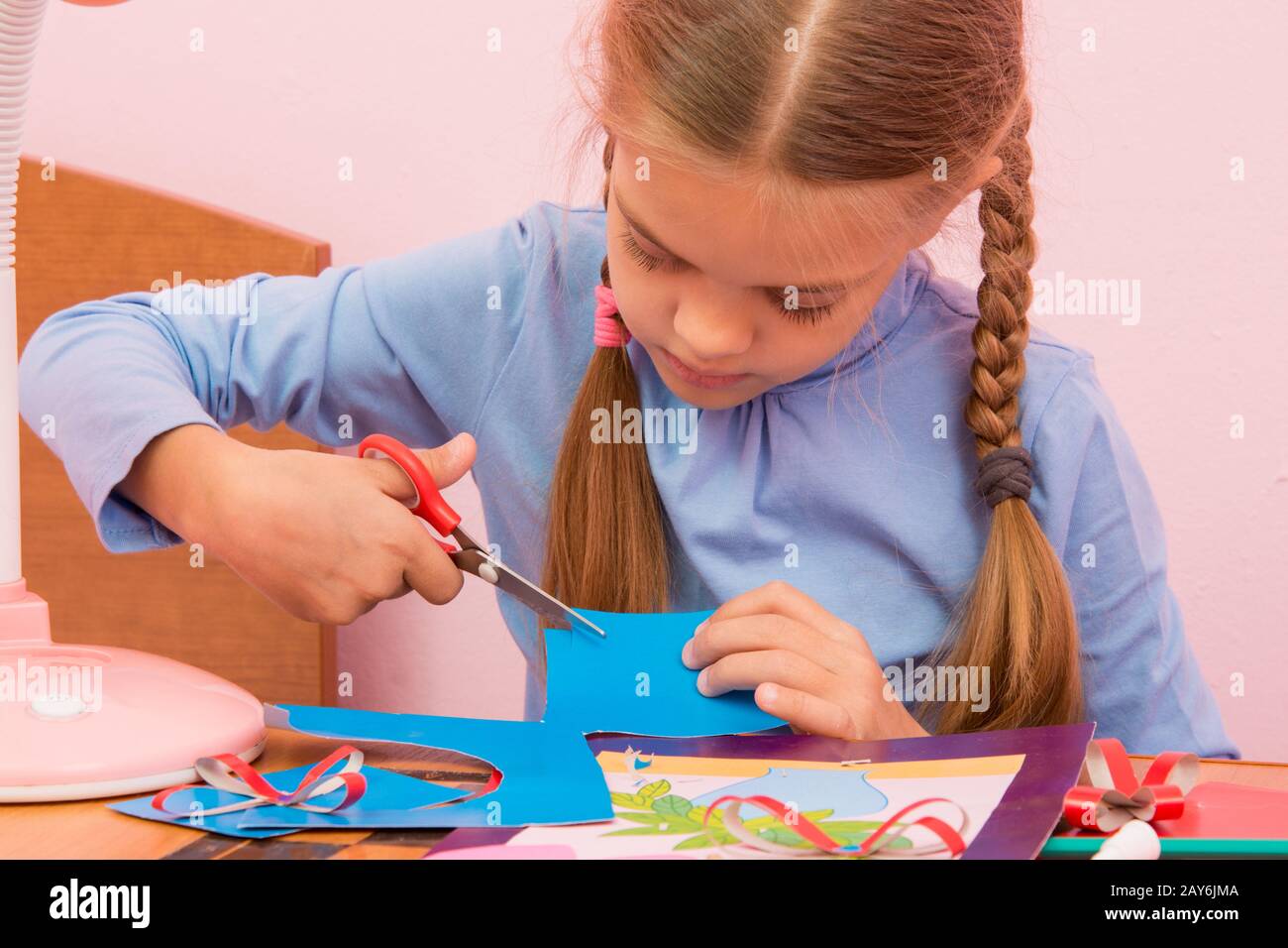 Il bambino taglia un pezzo di blu e di cartoncino colorato Foto Stock