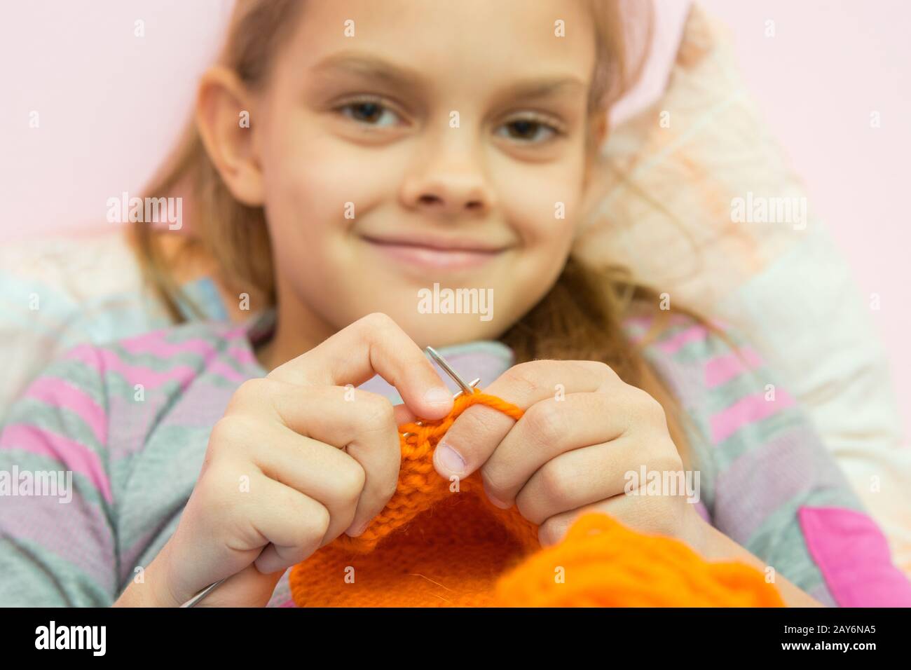 Happy girl maglieria sugli aghi e guardato dentro il telaio, la telecamera si concentra sulle razze Foto Stock