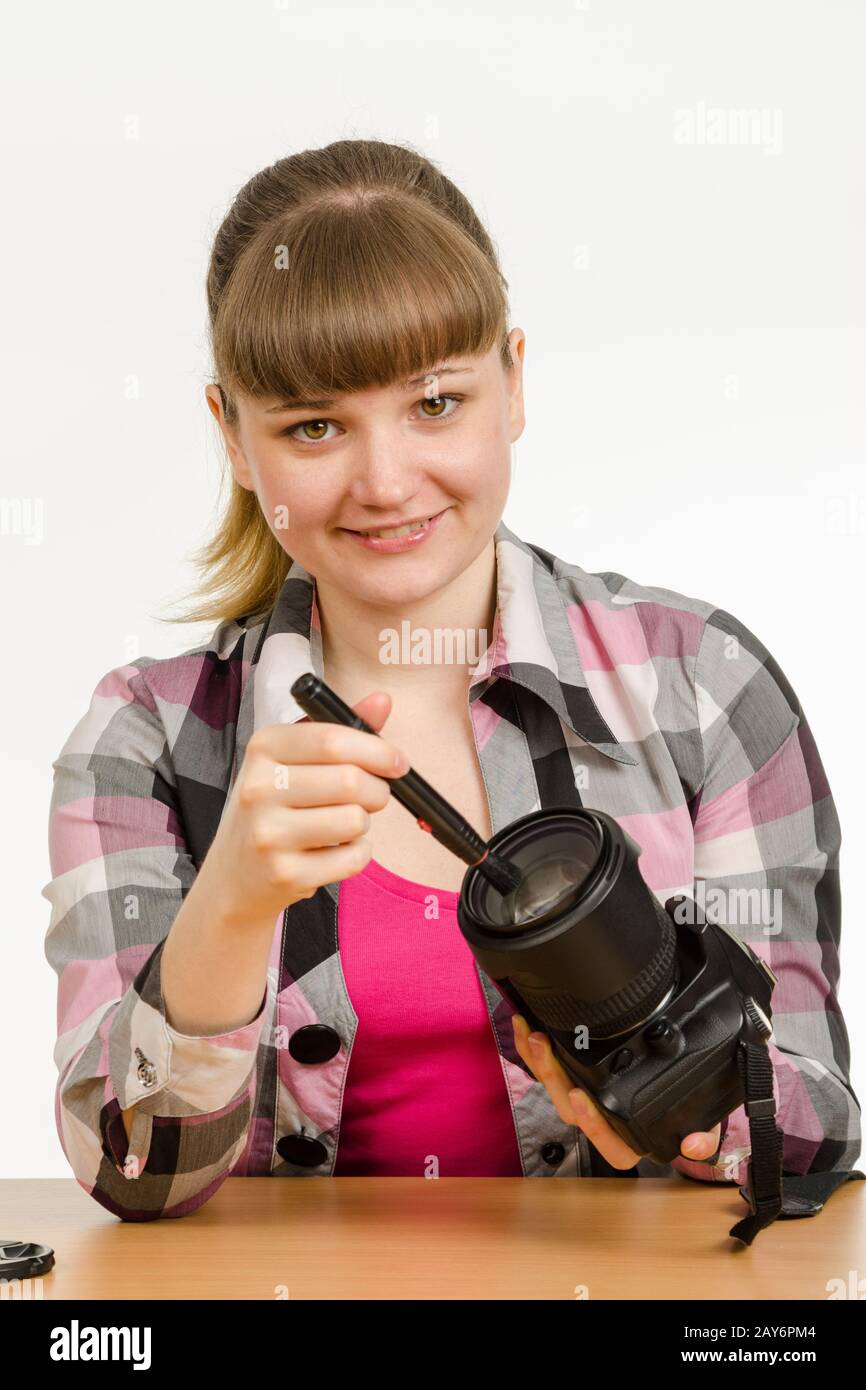 Fotografo pulisce la parte anteriore della lente della fotocamera e guardato dentro il telaio Foto Stock