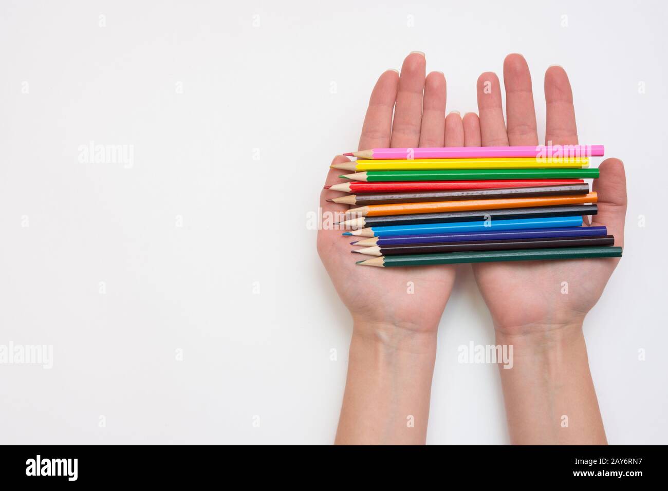 Mano femminile che tiene nelle sue mani una dozzina di matite, mani destra, sinistra uno spazio vuoto al di sotto del titolo Foto Stock