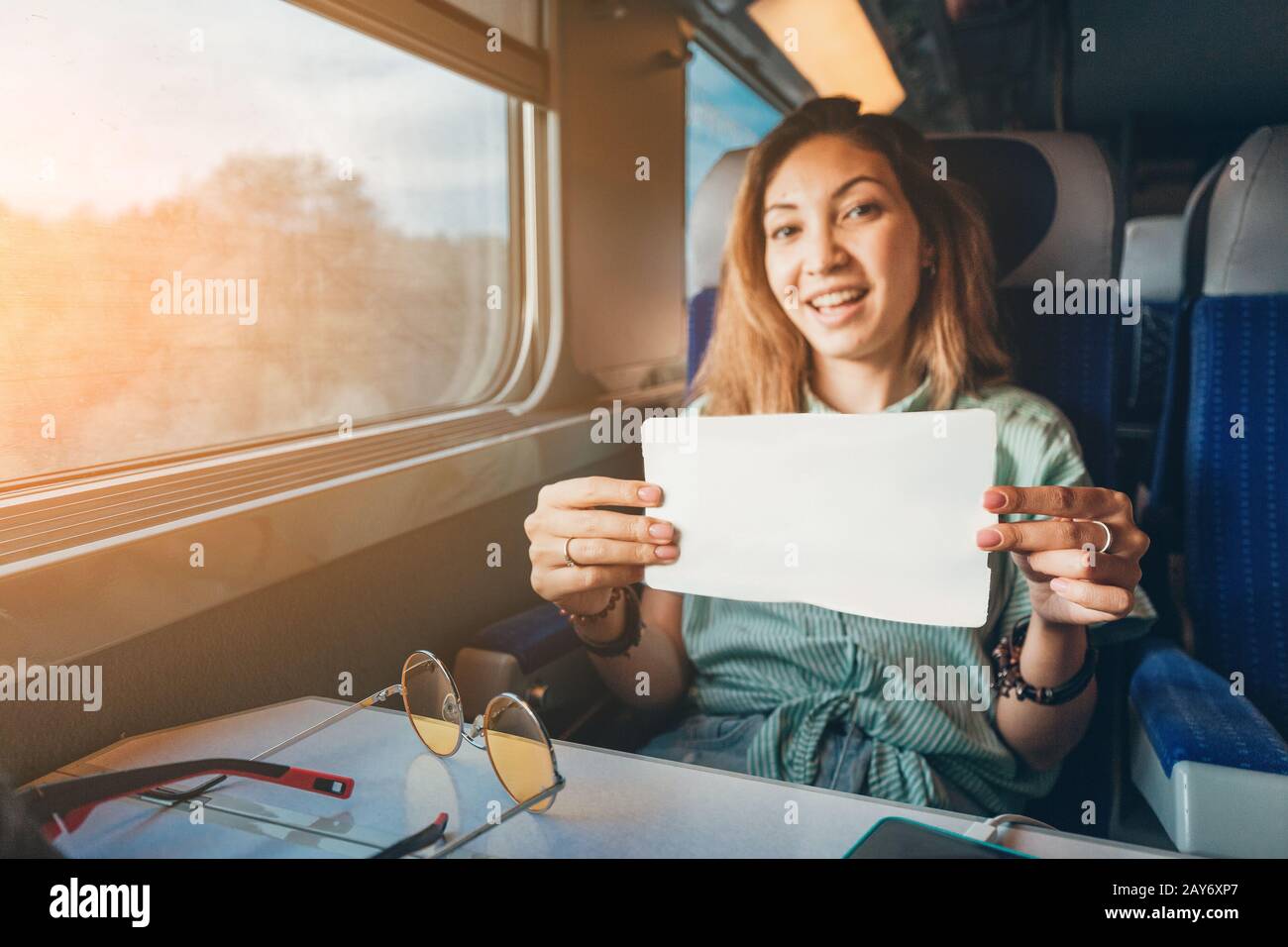 Giovane donna asiatica che viaggia in treno e mostra il suo biglietto per il direttore d'orchestra Foto Stock