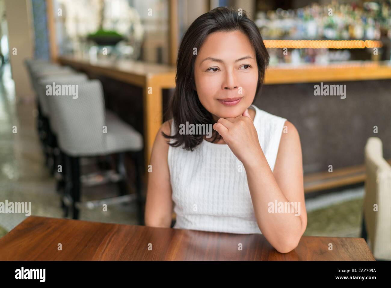 Elegante ritratto pensivo asiatico di mezza età. Bella matura cinese business donna rilassante nel bar ristorante urbano elegante vivere a Shanghai, Cina. Concetto di consapevolezza. Foto Stock