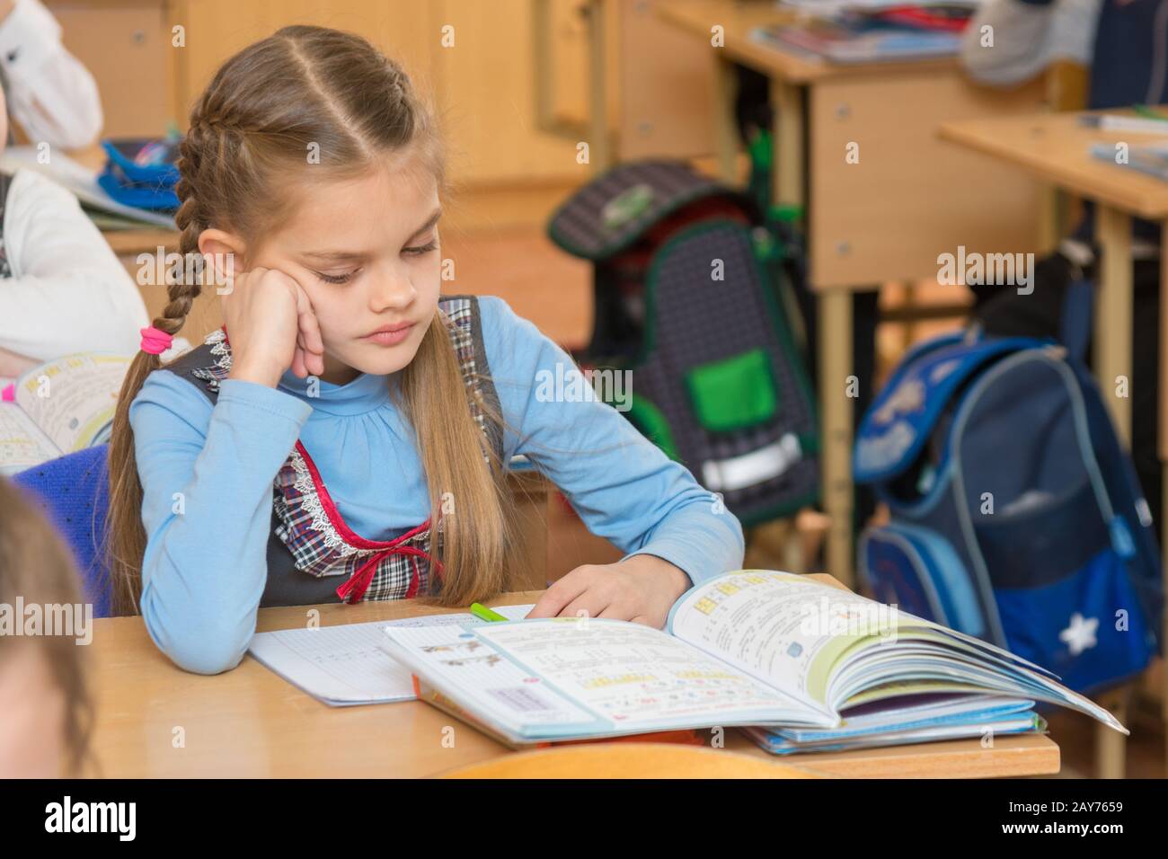 Una ragazza allievo in aula a scuola guardando un libro di testo Foto Stock