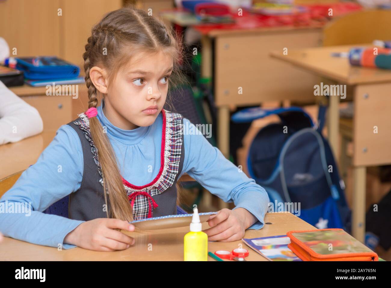 La ragazza di scuola per la classe del lavoro non ha capito il compito e con un perplesso guardando insegnante Foto Stock