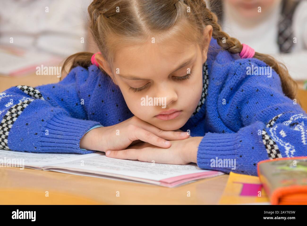 Primo classificatore per leggere la lezione legge il testo nel libro con la testa tra le mani Foto Stock