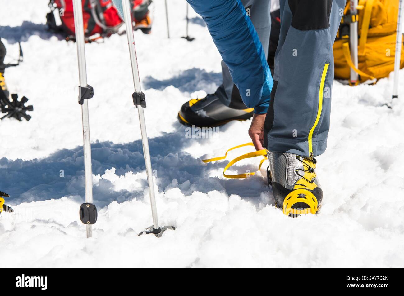 Un giovane uomo che indossa abiti da arrampicata Crampons su scarpe da alpinismo Per camminare attraverso il ghiacciaio Foto Stock