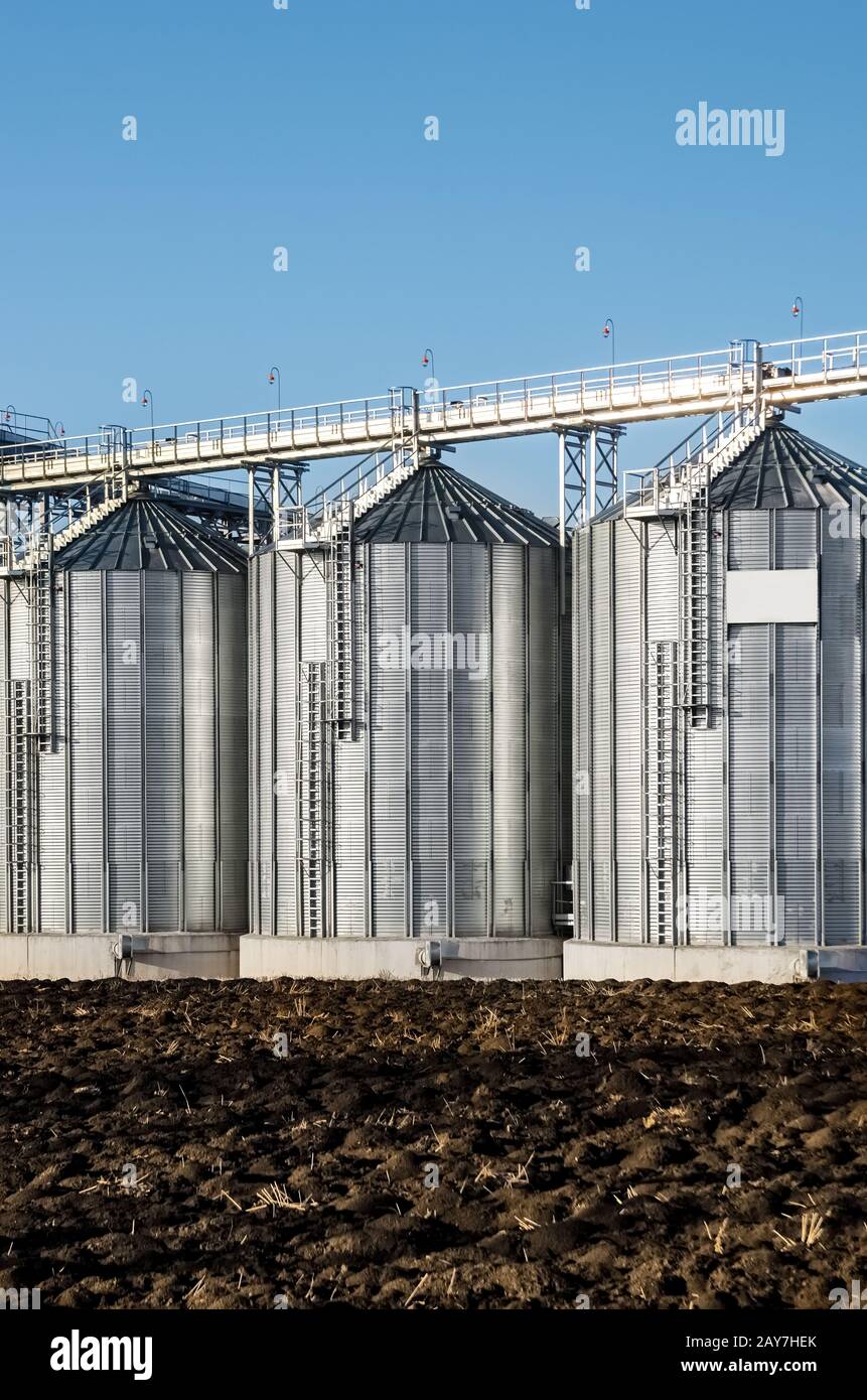 I complessi impianti di silo per lo stoccaggio di grano in piedi nell'arato Foto Stock