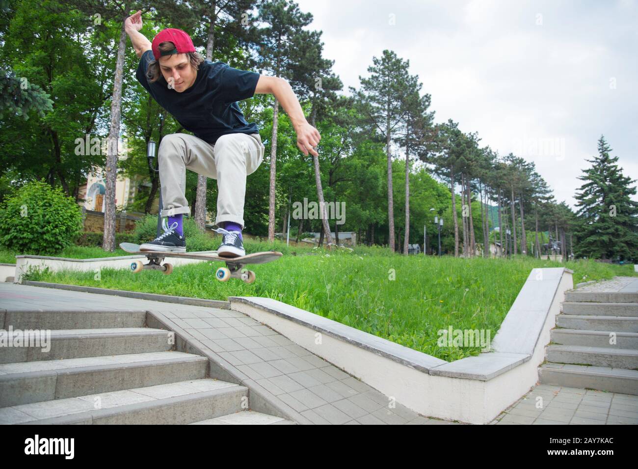 Skater-teenager dai capelli lunghi in una T-shirt e un cappello da sneaker  salta un vicolo contro un cielo tempestoso Foto stock - Alamy