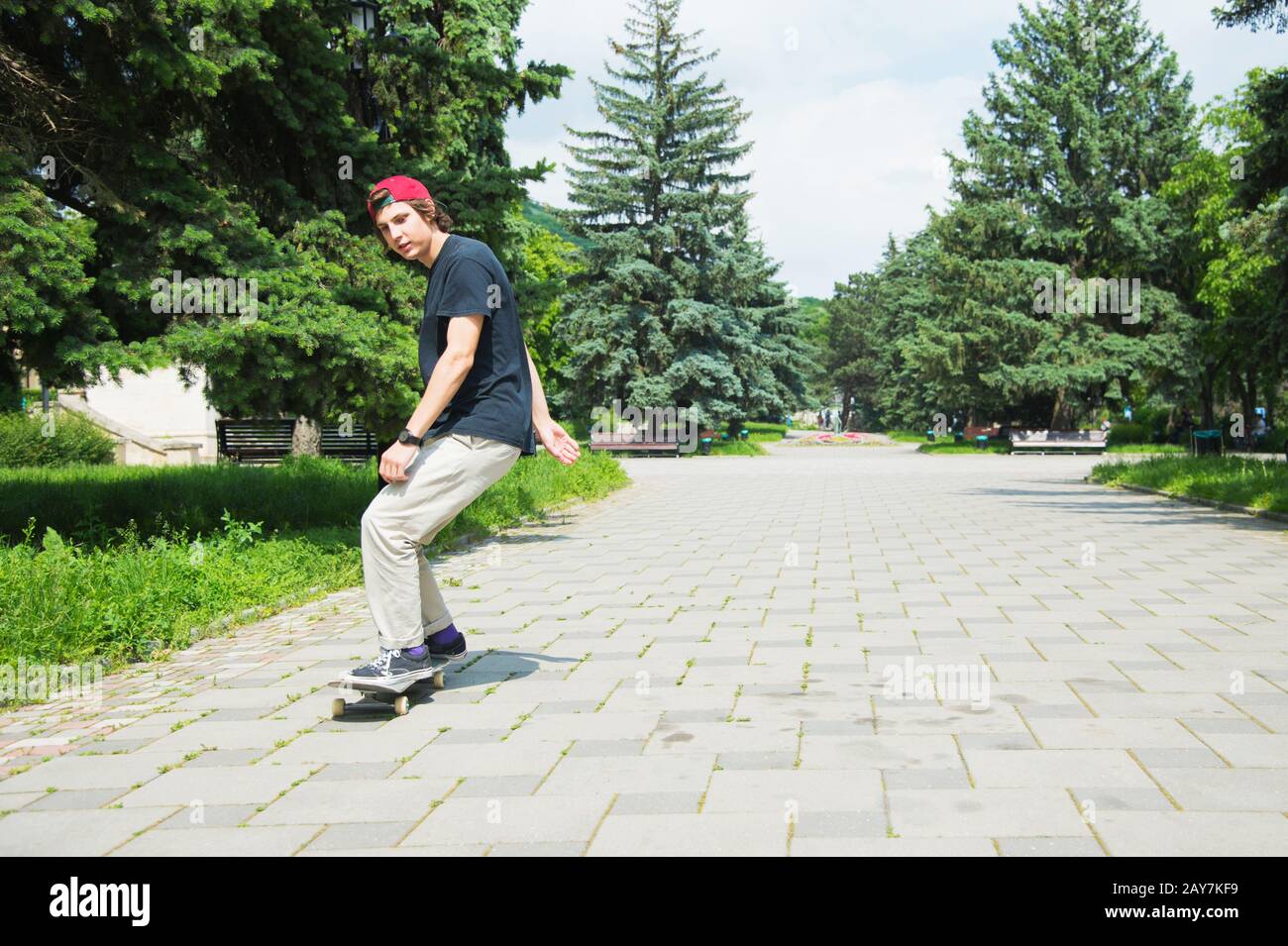 Skater-teenager dai capelli lunghi in una T-shirt e un cappello da sneaker  salta un vicolo contro un cielo tempestoso Foto stock - Alamy
