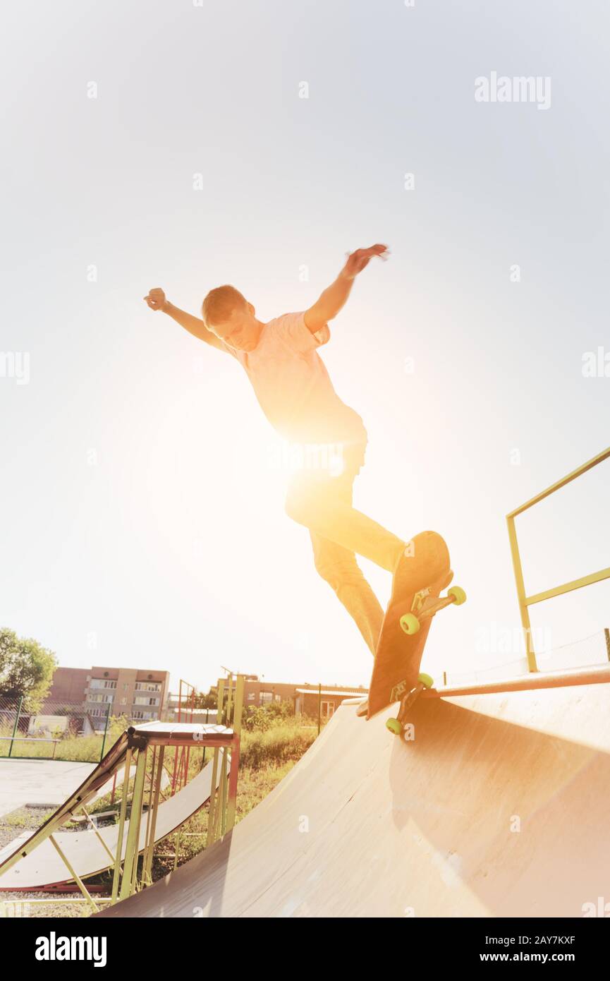 Skater teen appendere su una rampa su uno skateboard in un parco skateboard Foto Stock