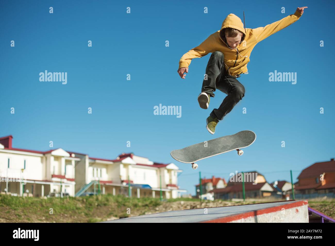 Un teenager skateboarder fa un trucco a scatto in uno skatepark alla periferia della città Foto Stock