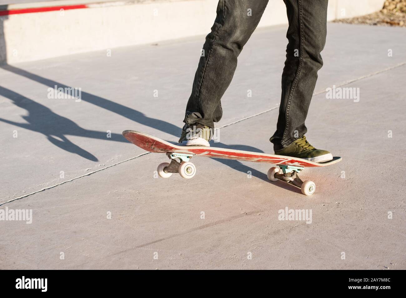 Un ragazzo giovane su uno skateboard in un manuale su uno skatepark sullo sfondo della casa Foto Stock