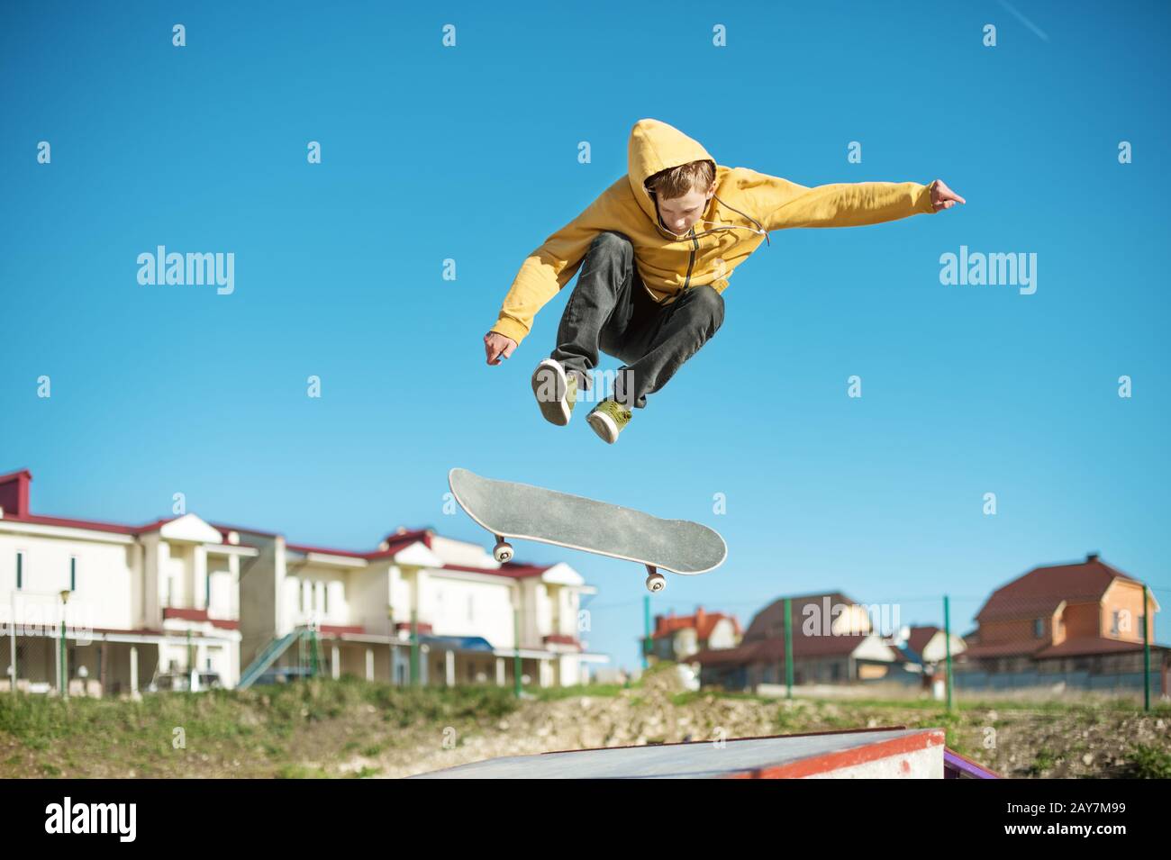 Un teenager skateboarder fa un trucco a scatto in uno skatepark alla periferia della città Foto Stock