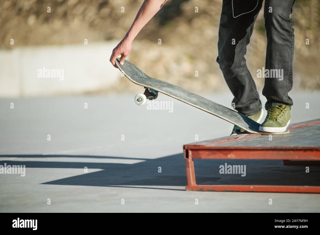 Un ragazzo giovane su uno skateboard in un manuale su uno skatepark sullo sfondo della casa Foto Stock