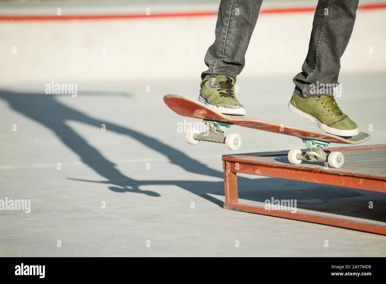 Un ragazzo giovane su uno skateboard in un manuale su uno skatepark sullo sfondo della casa Foto Stock