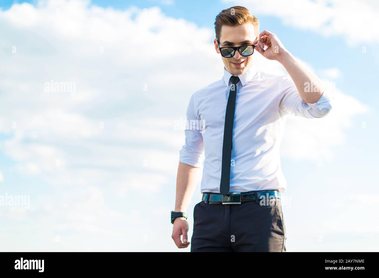 Serio giovane busunessman in camicia bianca, cravatta e occhiali da sole sta Foto Stock