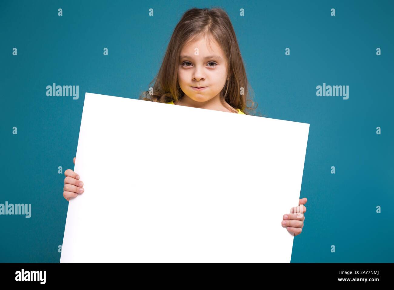 Cute bambina in maglietta con capelli marrone tenere carta pulita Foto Stock