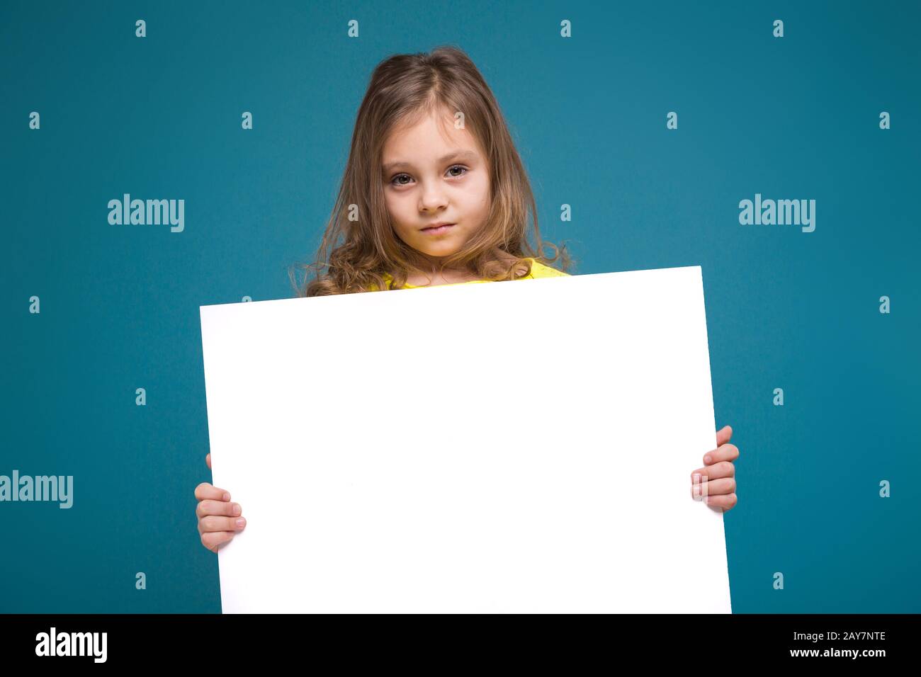 Cute bambina in maglietta con capelli marrone tenere carta pulita Foto Stock