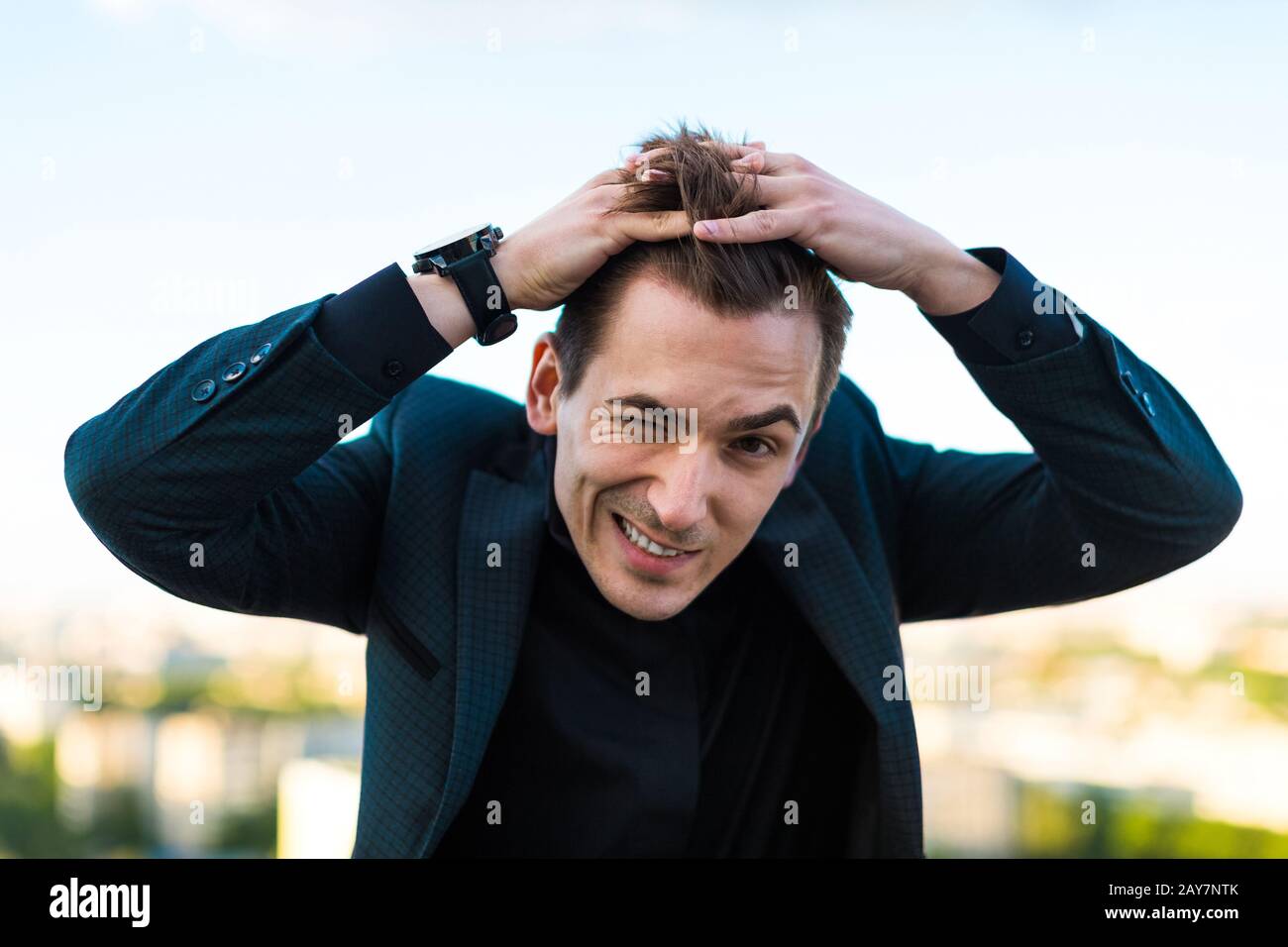 Giovane uomo d'affari serio in abito scuro, orologio e camicia nera st Foto Stock