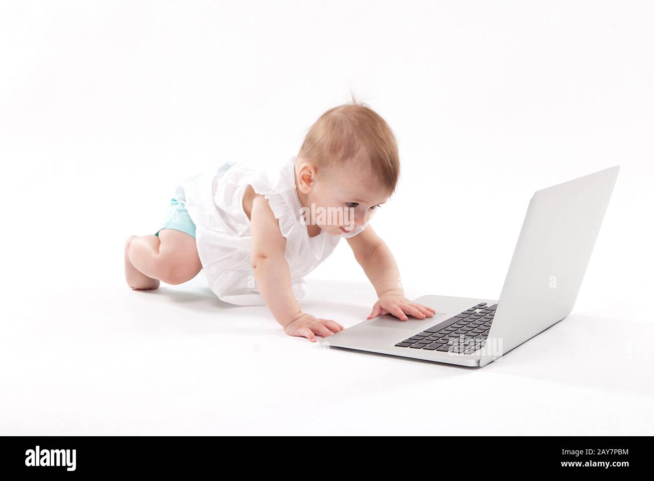 Curioso sorridente bambino seduto vicino al portatile su un backgro bianco Foto Stock