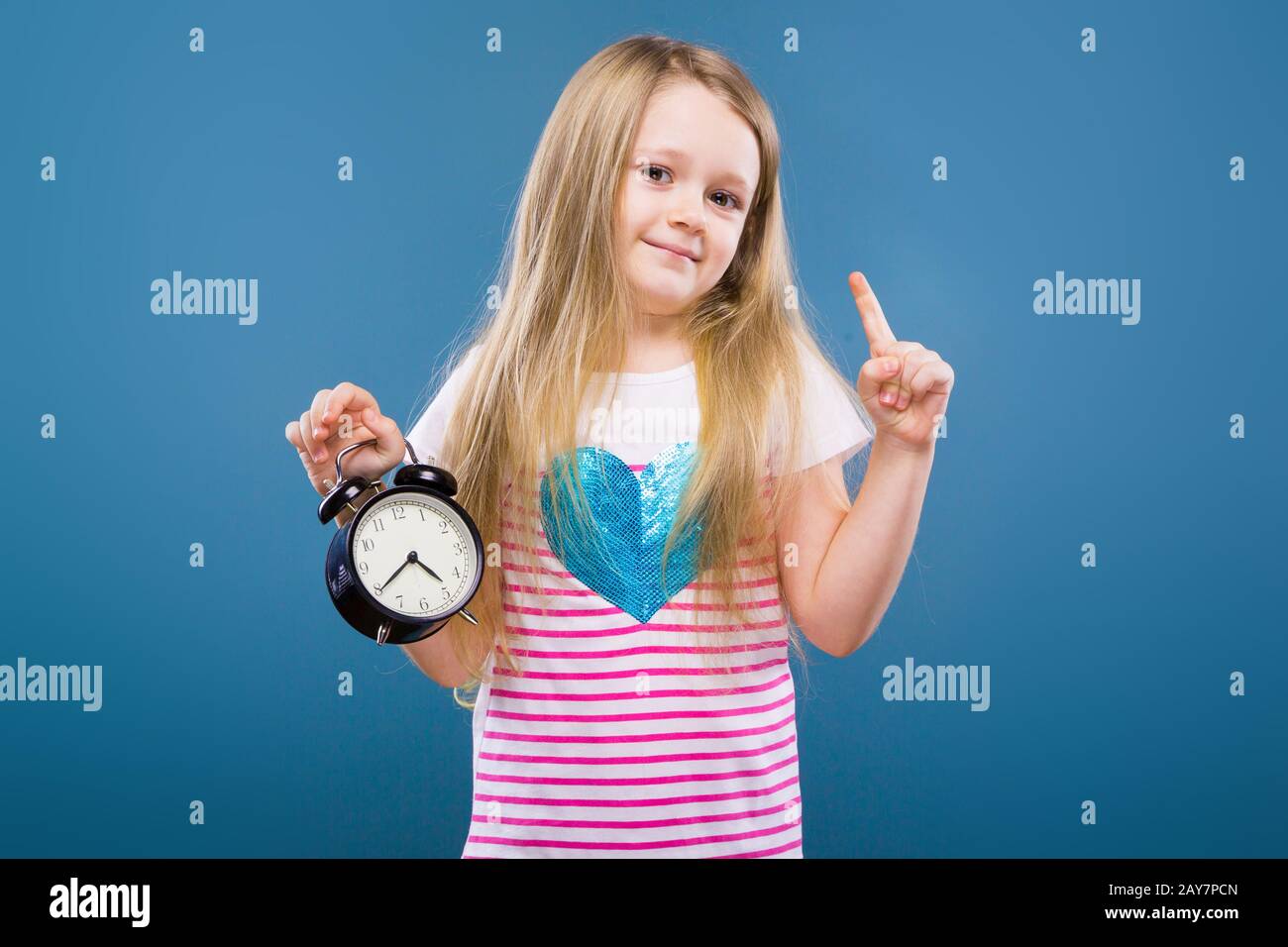 Adorabile bambina in camicia a righe bianche con cuore blu e jeans tenere sveglia Foto Stock