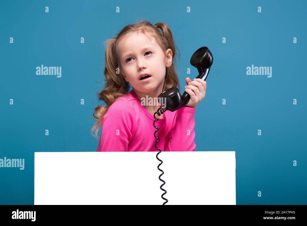 Attraente bambina carina in camicia rosa con scimmia e pantaloni blu tenere  poster vuoto e parla un telefono Foto stock - Alamy