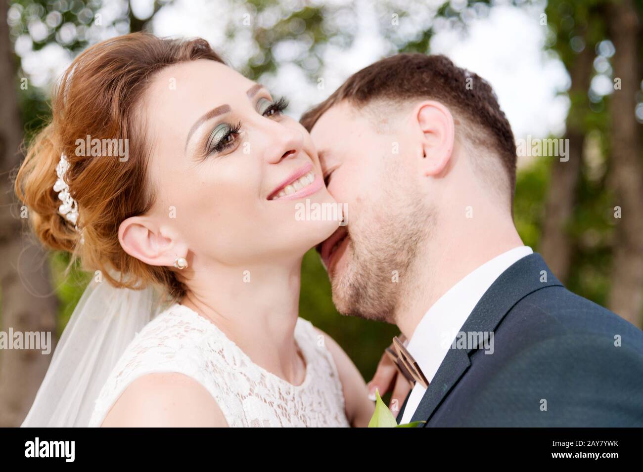 Primo piano ritratto di una bella coppia amorevole baciare newlyweds su uno sfondo di verde estate Foto Stock