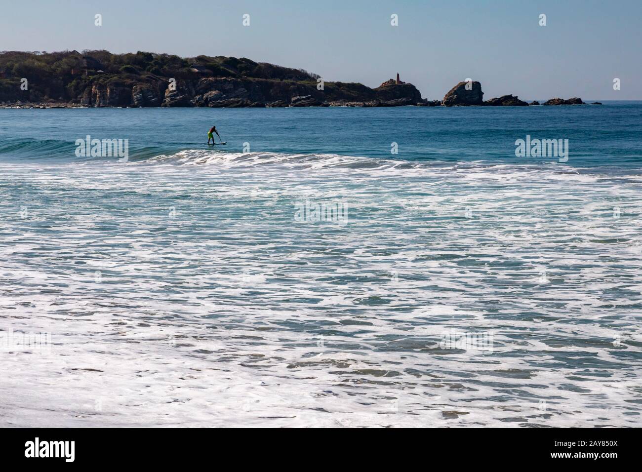 Brisas de Zicatela, Oaxaca, Messico - un uomo pagaia una tavola da surf sull'Oceano Pacifico. Foto Stock