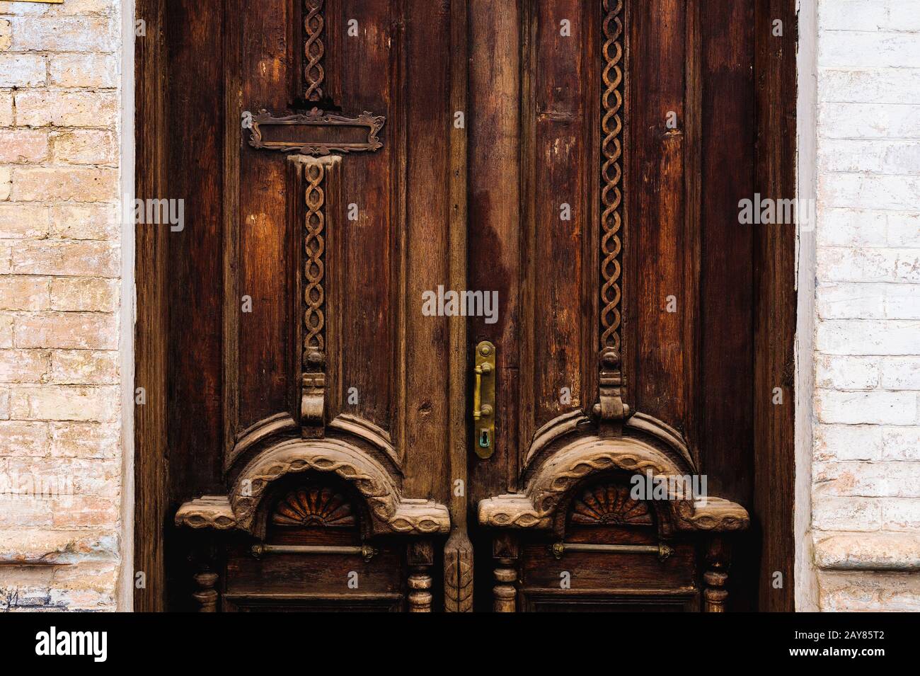 Sfondo vintage. Vecchia maniglia in ottone con elementi di una porta in legno intagliato decorata con massiccio tessuto in legno simulante Foto Stock