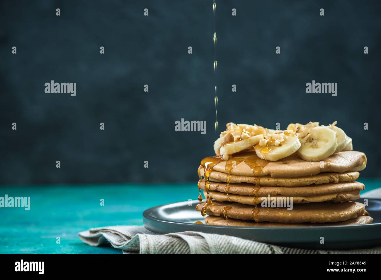 versando lo sciroppo di acero sopra il mucchio dei pancakes Foto Stock