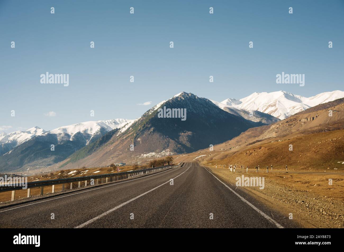 Vista della strada autunnale che conduce alle montagne fino alle vette innevate del Caucaso. Il concetto di viaggiare verso il monte Foto Stock