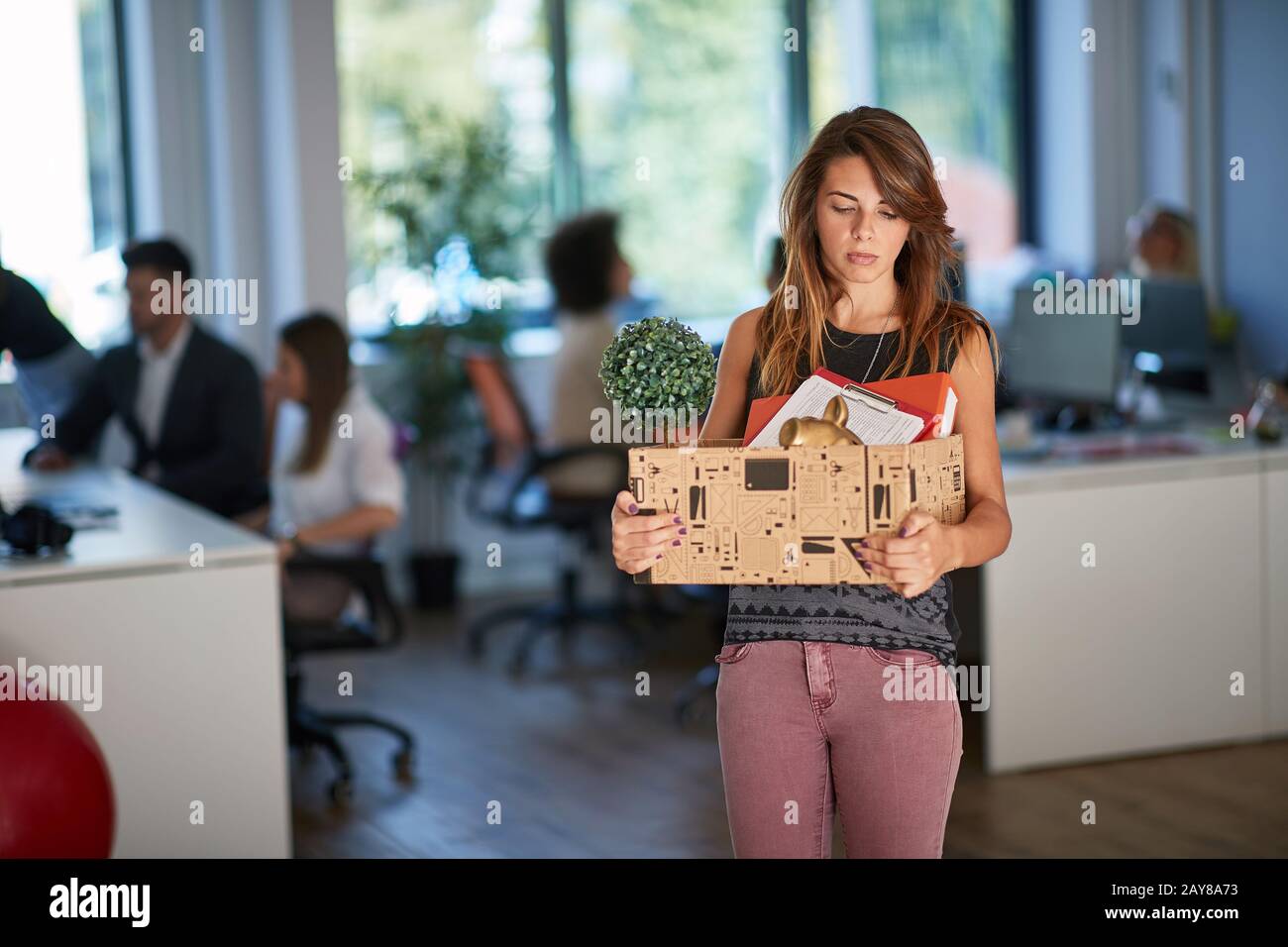 giovane femmina è sparato e si sposta fuori dall'ufficio, portando il suo roba nella scatola. fine, nuovo inizio Foto Stock