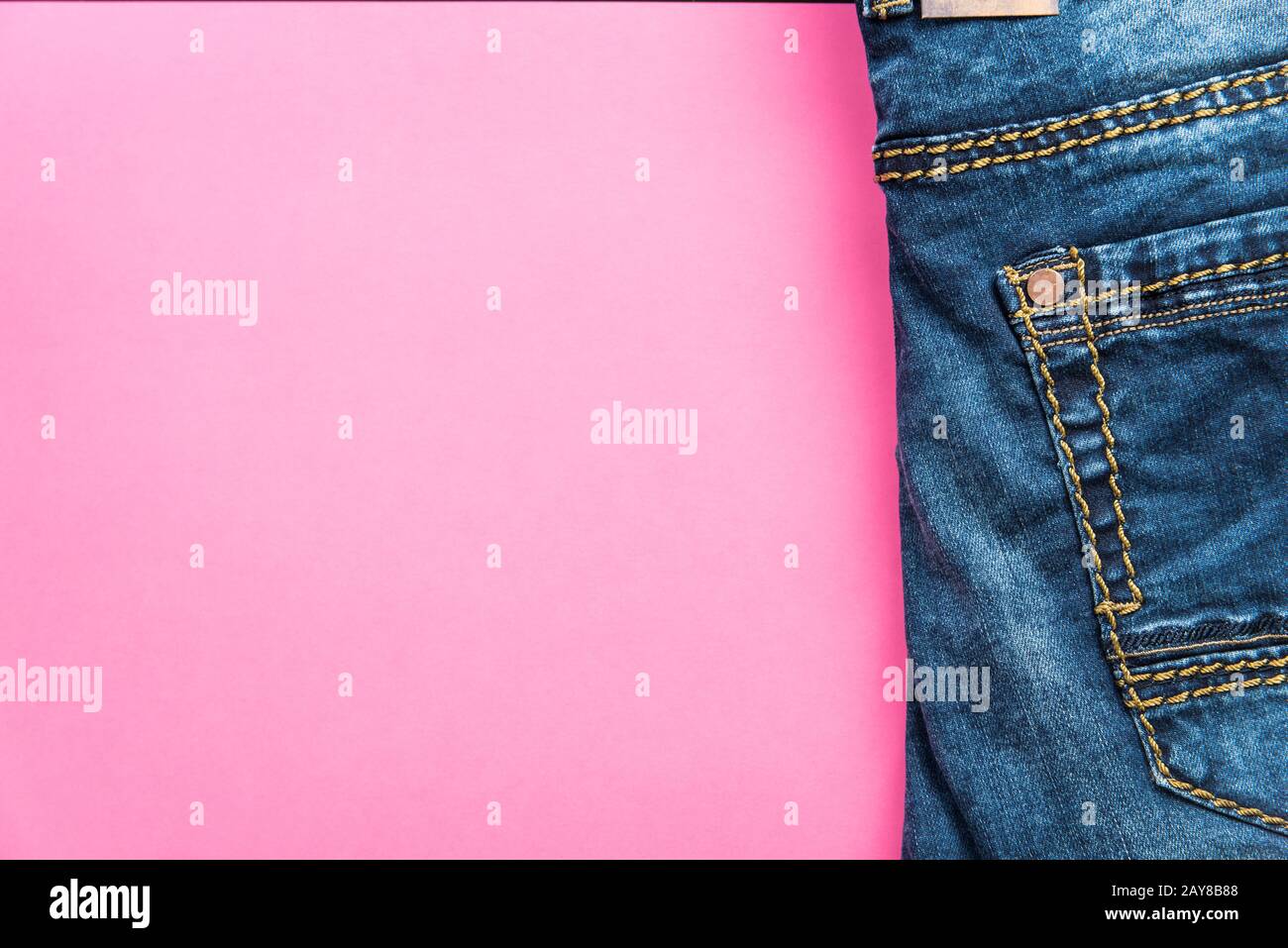 Jeans blu su sfondo rosa pastello Foto Stock