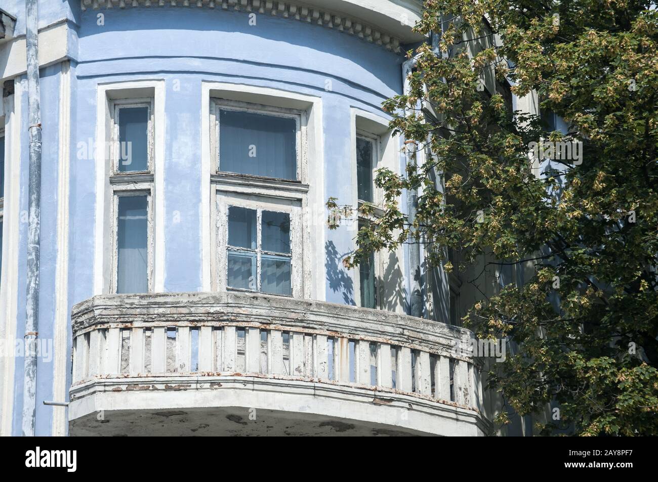 Finestre e balconi di trascurato il vecchio edificio con sbiadito e rovinosa blu facciata in gesso Foto Stock