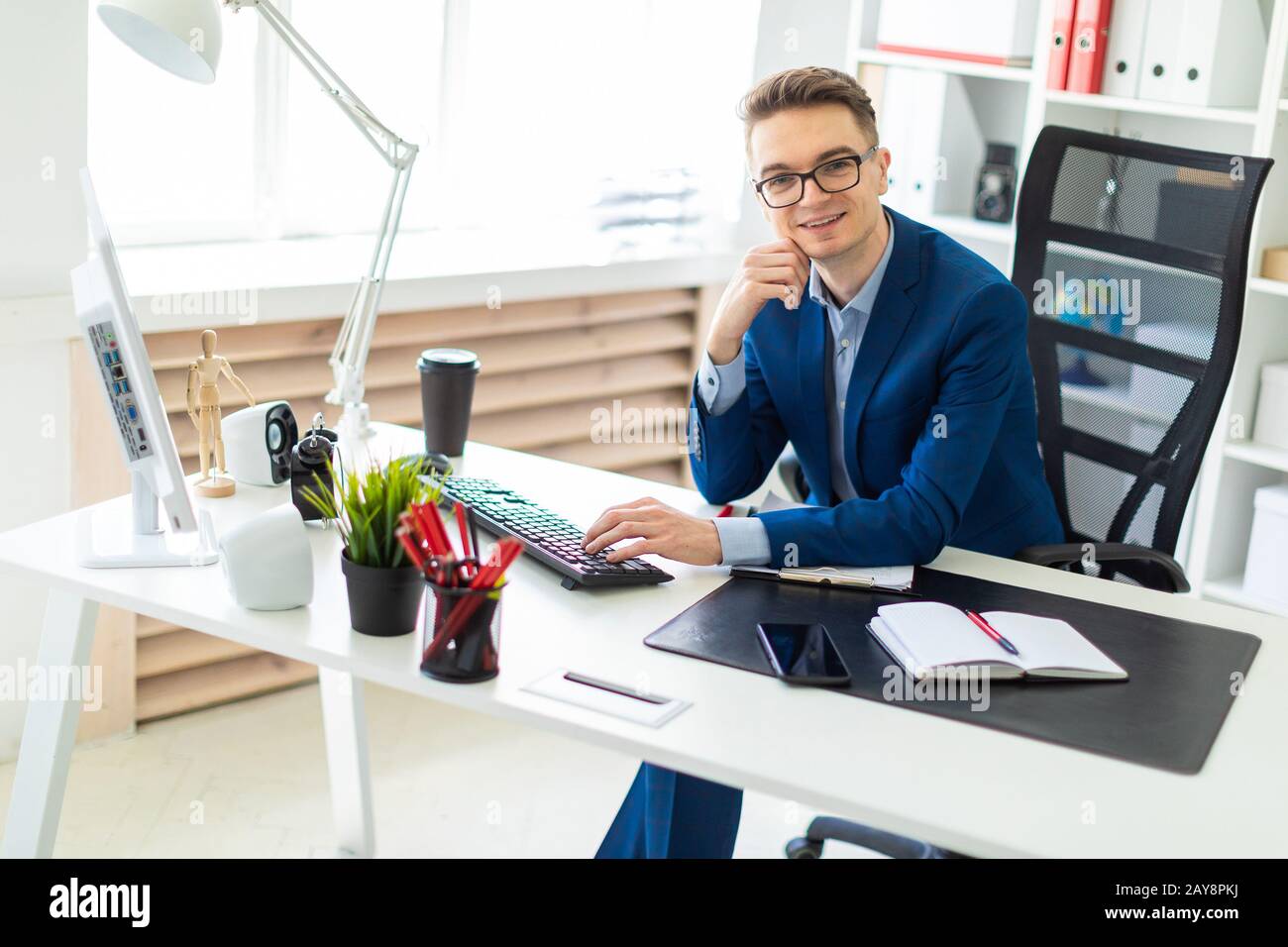 Giovane uomo seduto alla scrivania in ufficio e lavora sul computer. Foto Stock