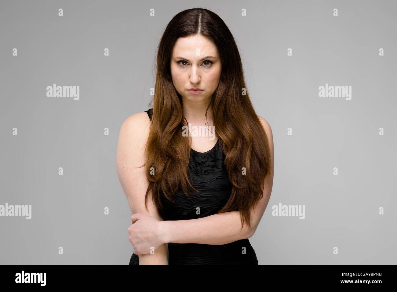 Attraente grave giovane arrabbiato brunette caucasian business donna in abito nero isolato su grigio Foto Stock