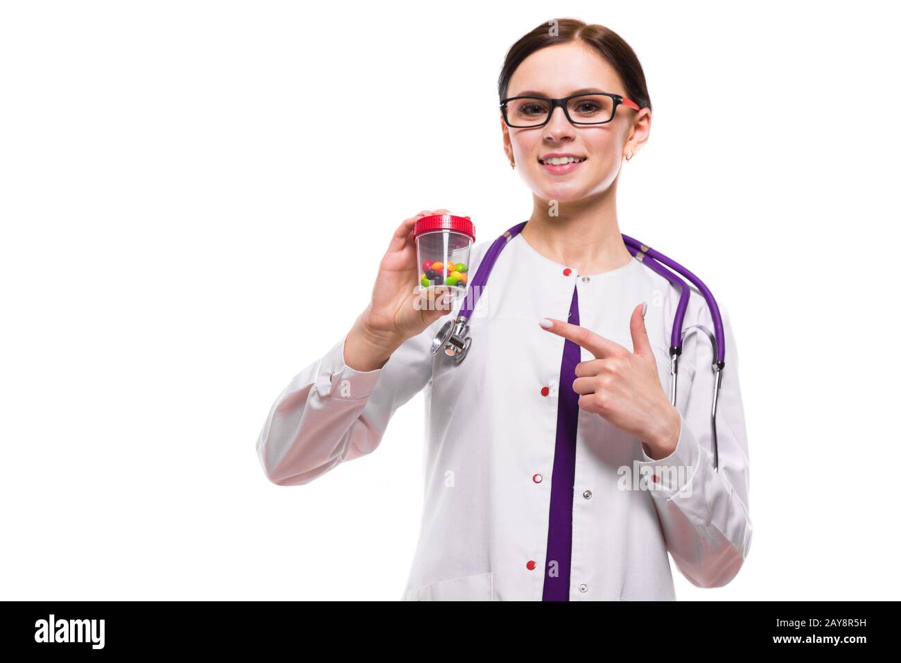 Giovani belle donne medico tenendo una bottiglia di pillole nelle sue mani su sfondo bianco Foto Stock