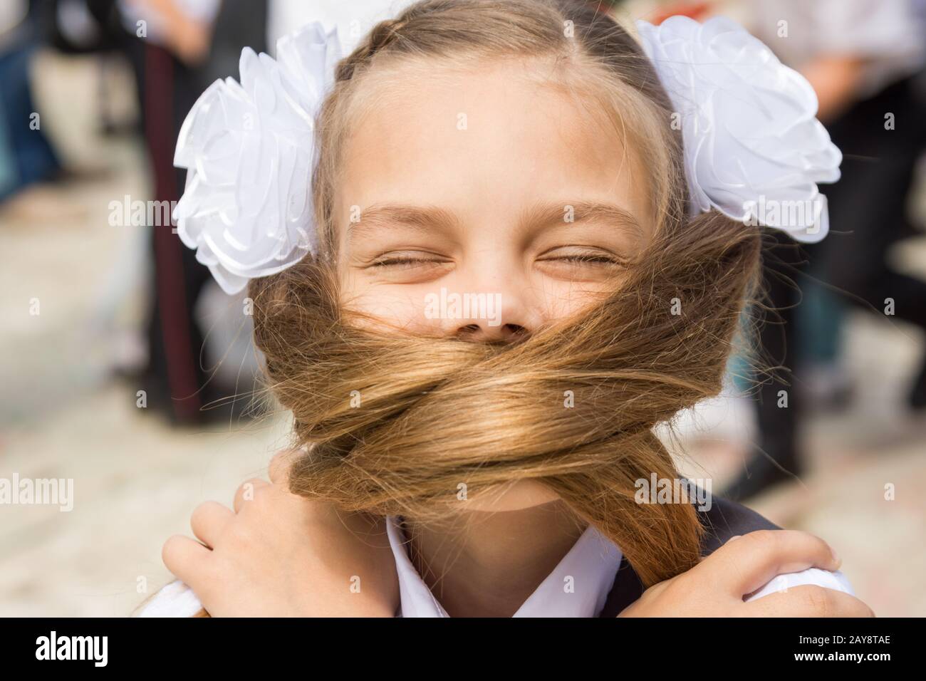 Il schoolgirl su una vacanza il 1 settembre il viso coperto con i suoi lunghi capelli Foto Stock