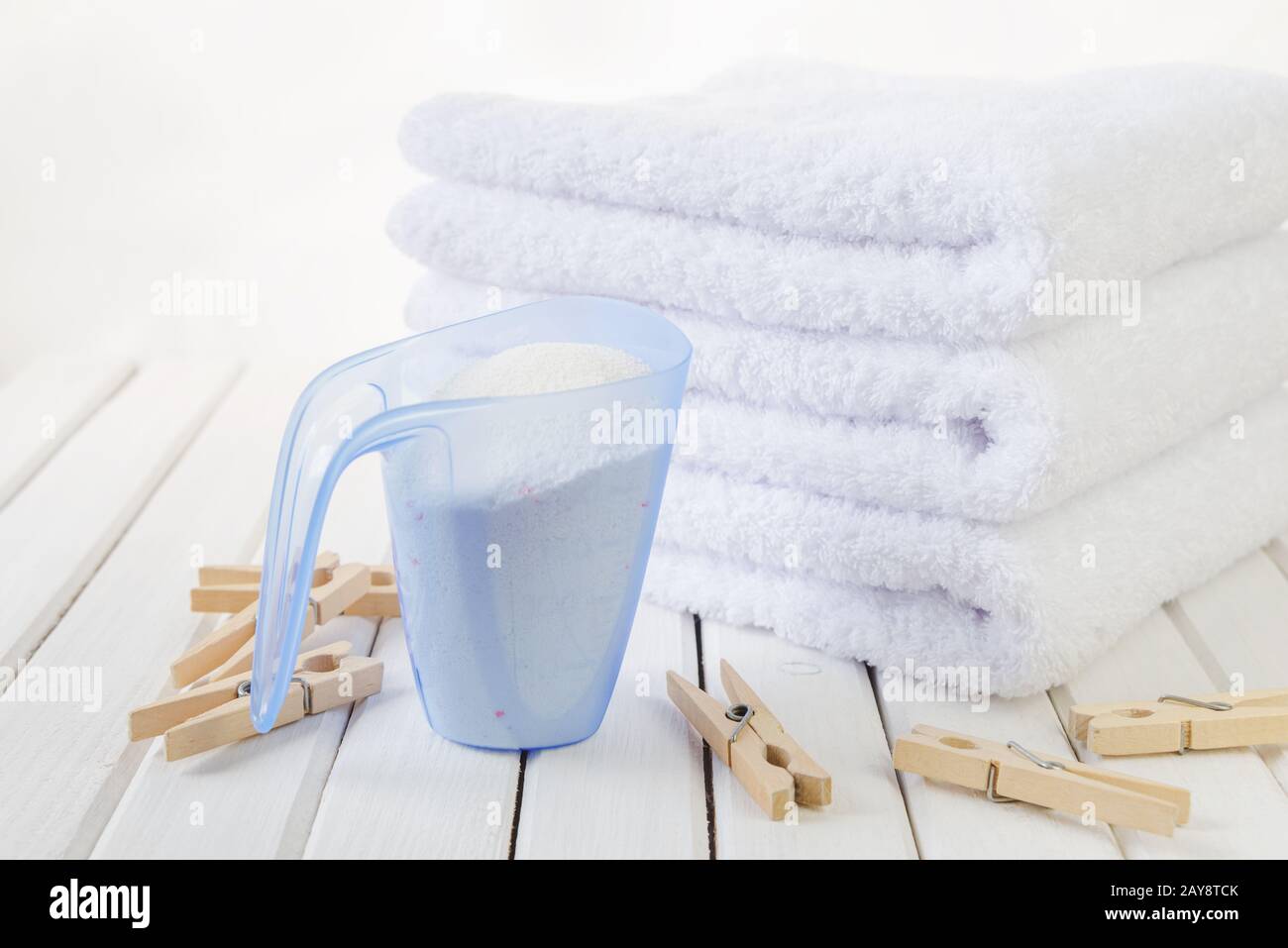 Asciugamani da bagno, detersivo in tazza graduata e zoccoli in legno Foto Stock