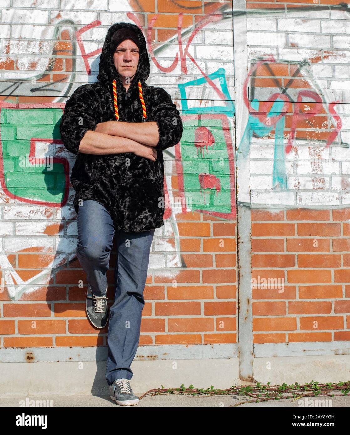 Posa di un modello uomo in pelliccia sintetica giacca di fronte a una parete graffiti Foto Stock
