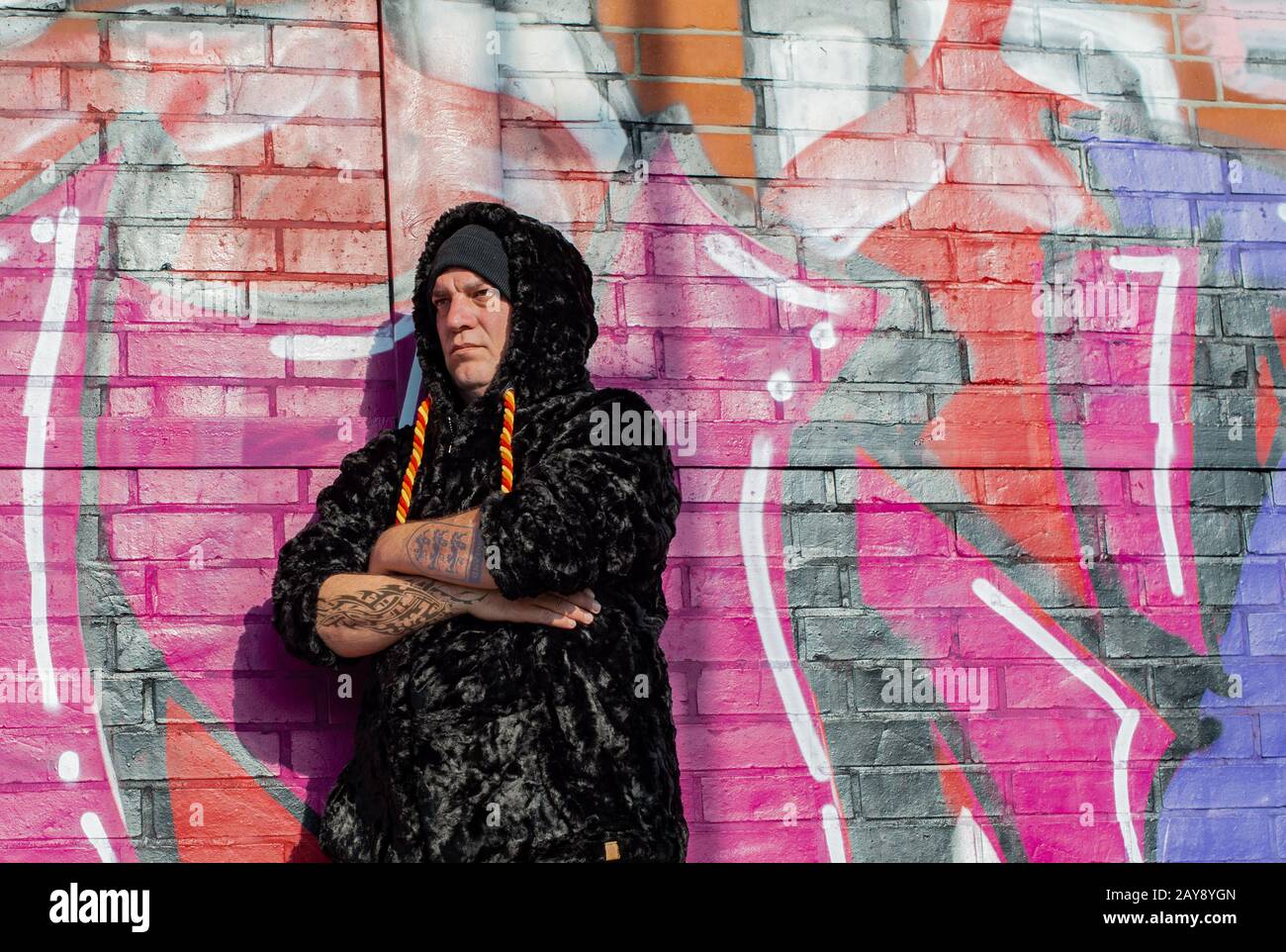 Posa di un modello uomo in pelliccia sintetica giacca di fronte a una parete graffiti Foto Stock