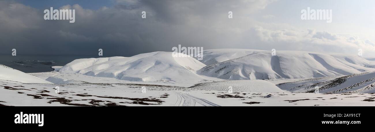 Panorama invernale della tundra pianura alluvionale del fiume che scorre tra la coperta di neve colline all'oceano Foto Stock