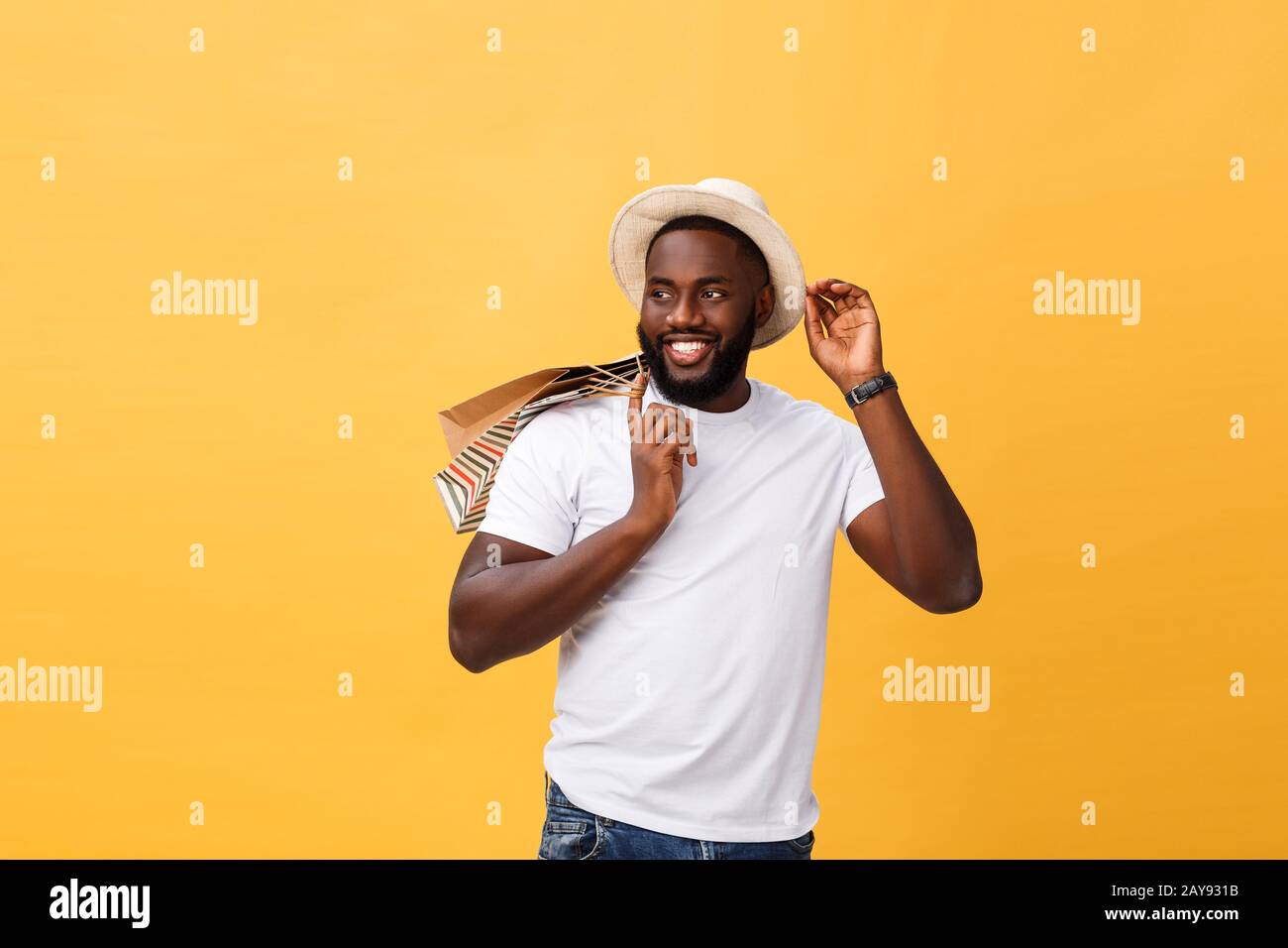 Felice African American uomo azienda shopping bags su sfondo giallo. Concetto di vacanza Foto Stock