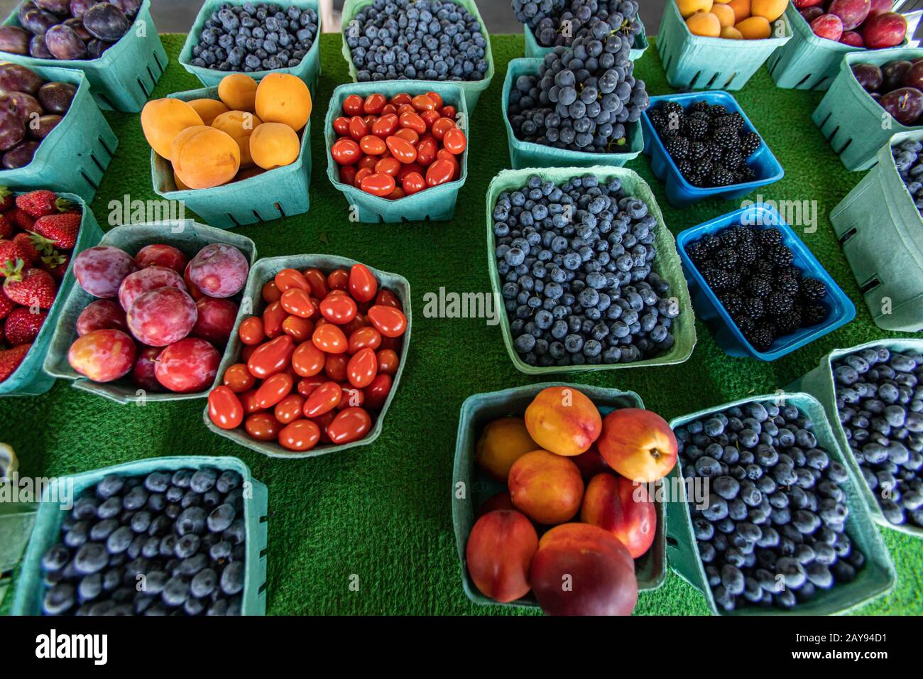 Vicino dall'alto di scatole di cartone e plastica di frutta e verdure. Mercato alimentare locale, buona varietà di articoli in vendita. Pomodori tra la frutta. Foto Stock
