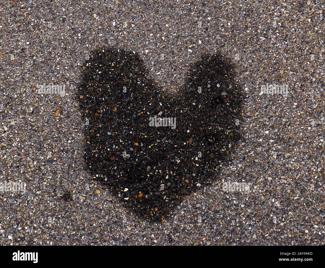 Macchia d'acqua a forma di cuore su pavimentazione di asfalto Foto Stock