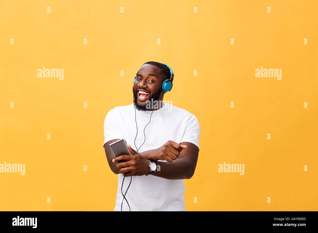 African American uomo con le cuffie per ascoltare e ballare con la musica. Isolato su sfondo giallo Foto Stock