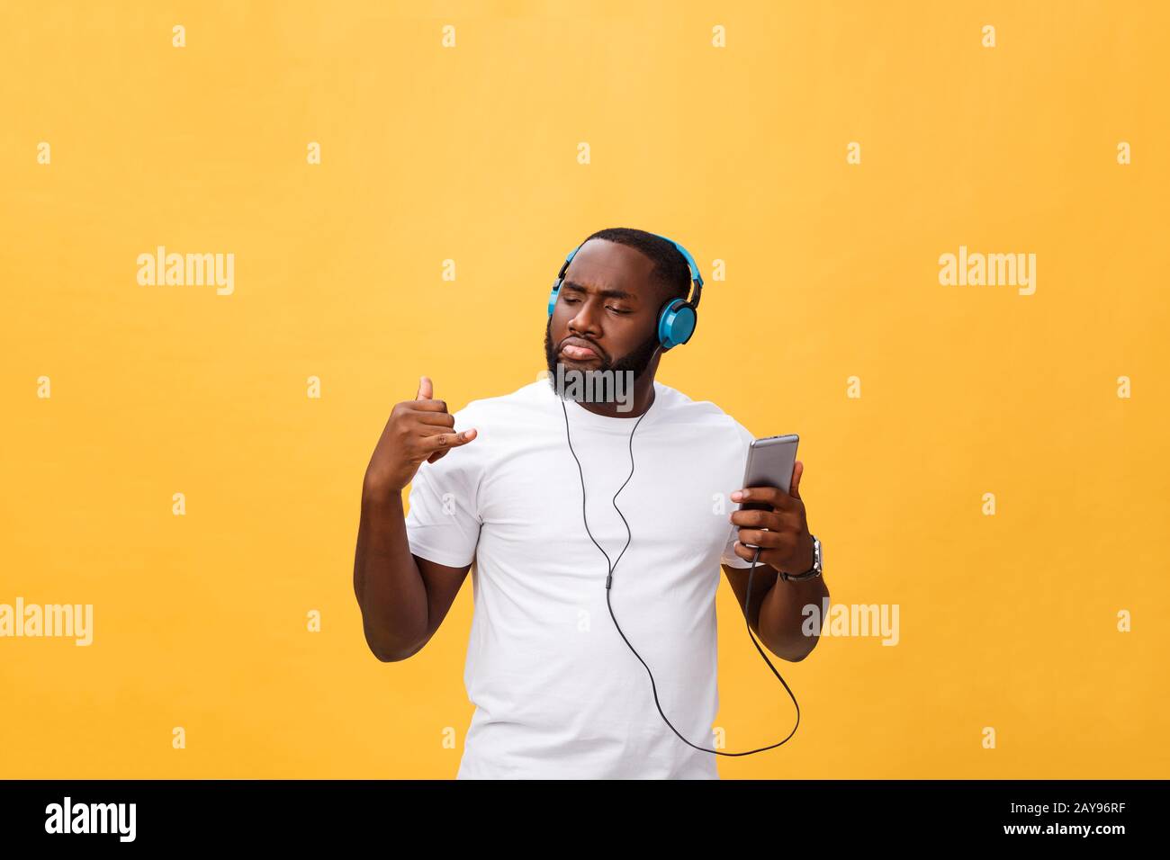 African American uomo con le cuffie per ascoltare e ballare con la musica. Isolato su sfondo giallo Foto Stock