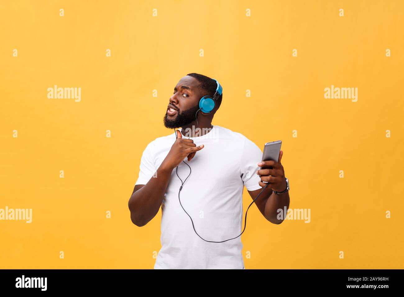 African American uomo con le cuffie per ascoltare e ballare con la musica. Isolato su sfondo giallo Foto Stock