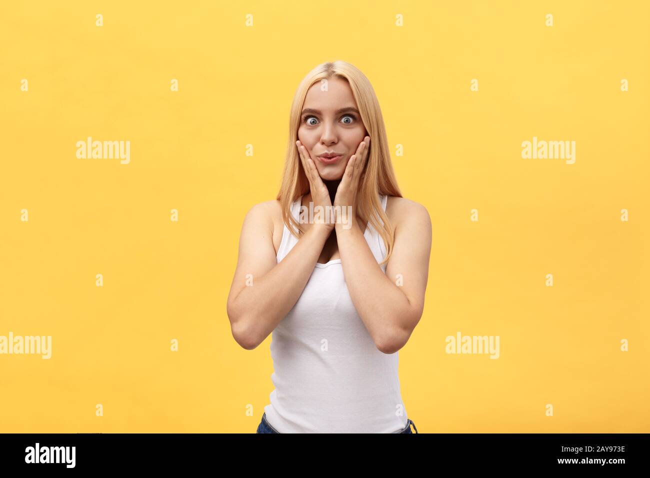 Giovane ragazza bionda con un look sorpreso su sfondo giallo. Immagine comprendente copia spazio per il testo Foto Stock